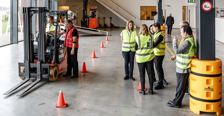 Frau fährt Stapler unter Aufsicht